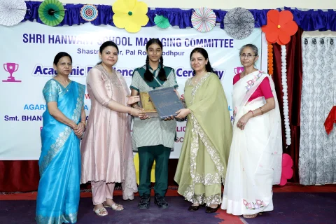 Student receiving award beside HSMC school leaders and chief guests